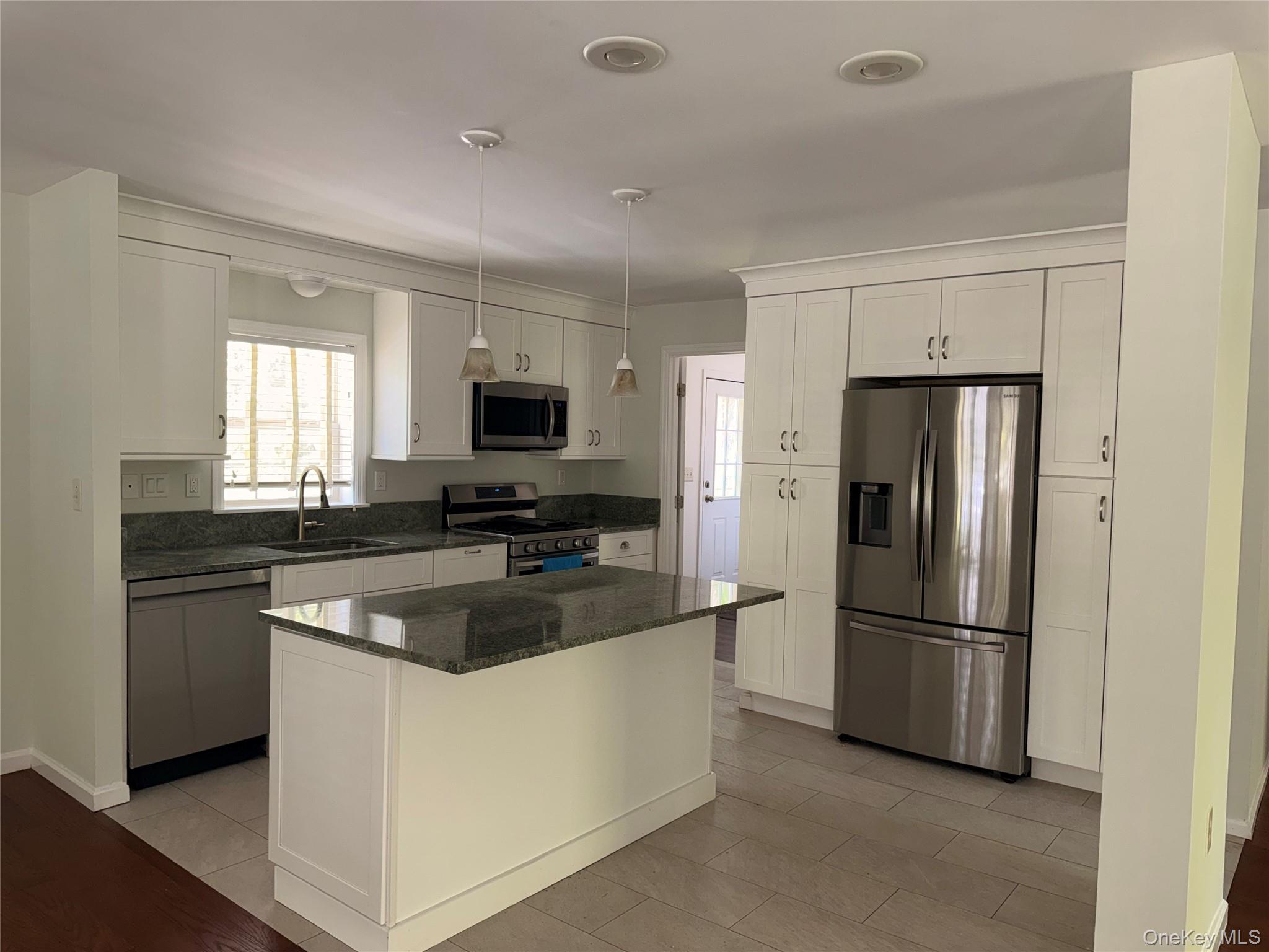 1661 Old Country Road, Unit 516 Riverhead, NY 11901 - Photo 12 of 50 a kitchen with granite countertop a refrigerator stove and microwave
