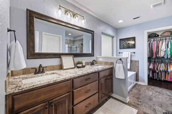 a en suite bathroom with a granite countertop double vanity sink and a two mirror