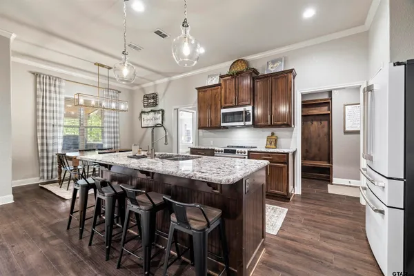 a kitchen with stainless steel appliances granite countertop a table chairs stove and refrigerator