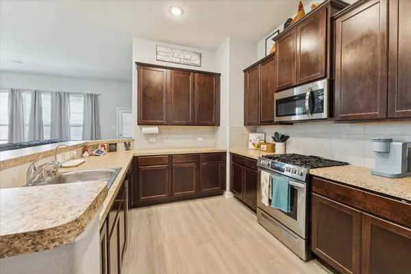 a kitchen with stainless steel appliances granite countertop wooden cabinets a stove top oven a sink and dishwasher