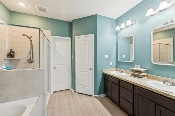 a spacious bathroom with a double vanity sink a mirror and a shower