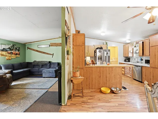 a living room with stainless steel appliances kitchen island granite countertop a sink and cabinets