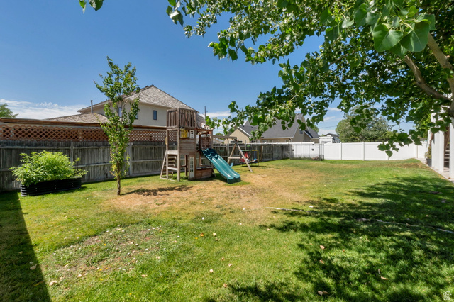 2013 West 460 South Provo, UT 84601 - Photo 24 of 24 Expansive backyard featuring a combination of wood and white vinyl fencing, mature trees, and a wooden play structure with a slide