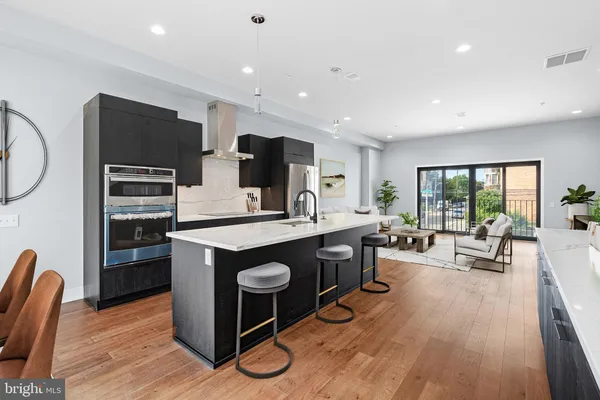 a kitchen with stainless steel appliances granite countertop a stove top oven a sink dishwasher a dining table and chairs with wooden floor