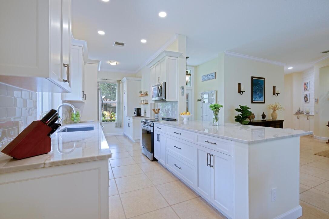 174 Hampton Circle Jupiter, FL 33458 - Photo 12 of 45 a large kitchen with stainless steel appliances kitchen island granite countertop a sink and white cabinets
