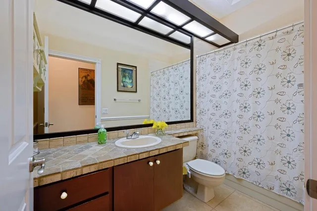 a bathroom with a granite countertop toilet sink and mirror