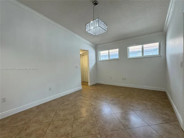 a view of an empty room with window and chandelier fan