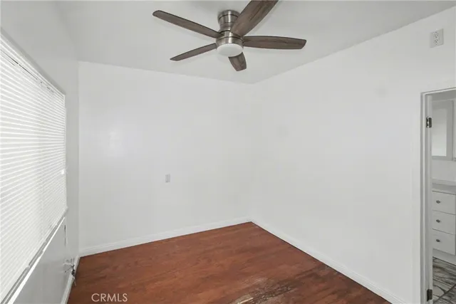 an empty room with a window and a ceiling fan