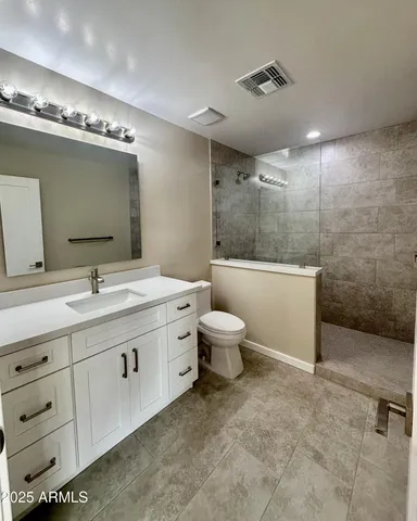 a spacious bathroom with a double vanity sink a toilet and a mirror