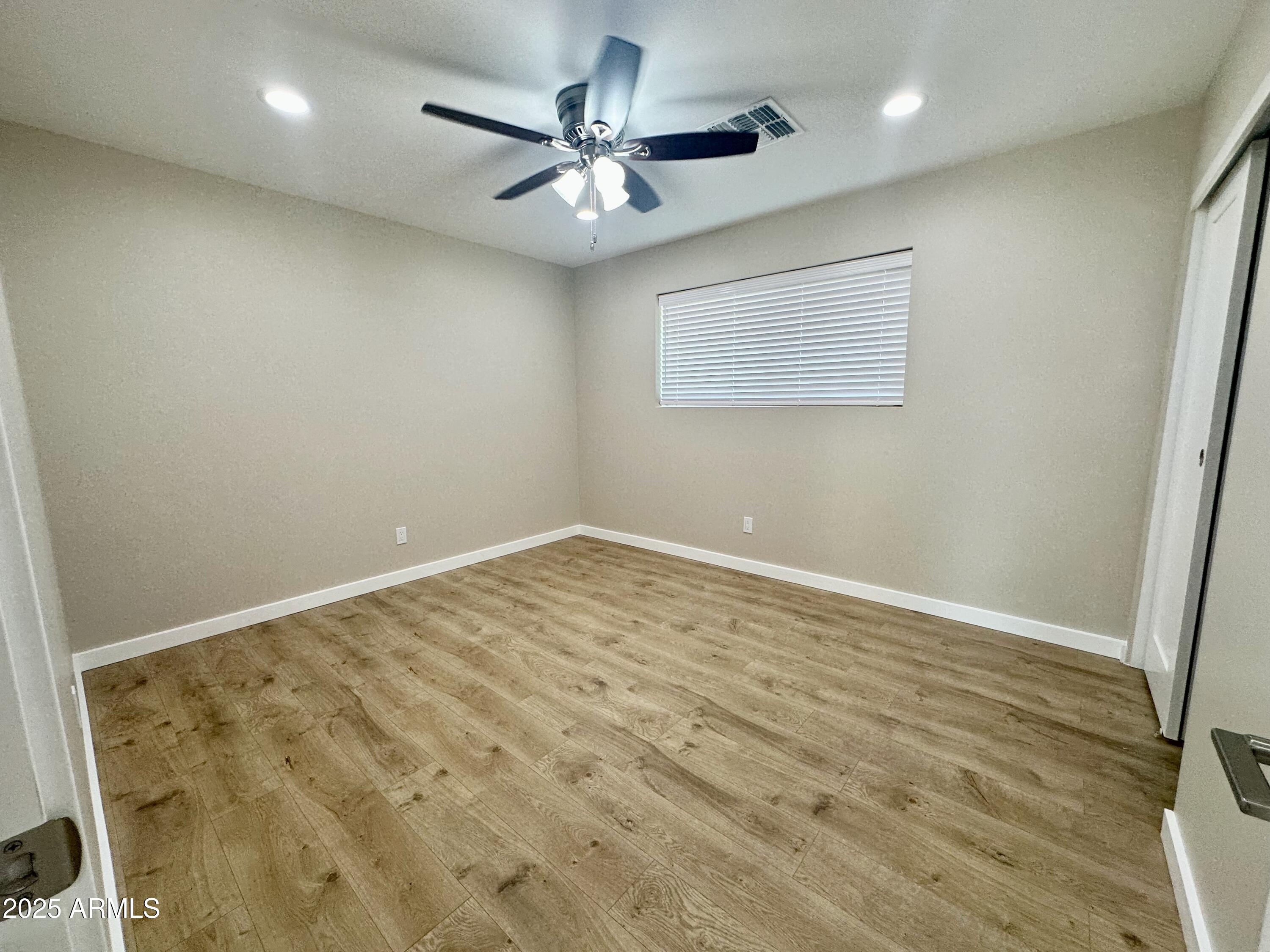 2329 East Enrose Street Mesa, AZ 85213 - Photo 24 of 30 an empty room with a ceiling fan and wooden floor