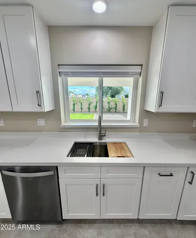 a kitchen with white cabinets a sink and a window