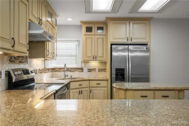 a kitchen with stainless steel appliances granite countertop a sink and a refrigerator