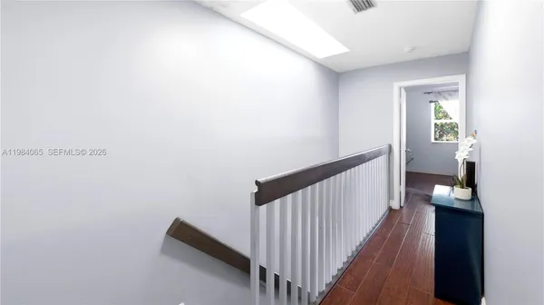 a view of a hallway to a room with wooden floor and stairs