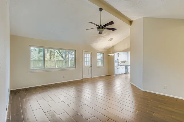 a view of an empty room with a window and wooden floor