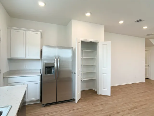 a kitchen with stainless steel appliances granite countertop white cabinets a sink a stove a microwave and wooden floors