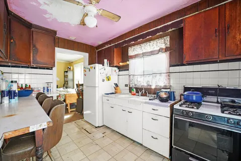 a kitchen with stainless steel appliances kitchen island granite countertop a stove a sink dishwasher and white cabinets with wooden floor