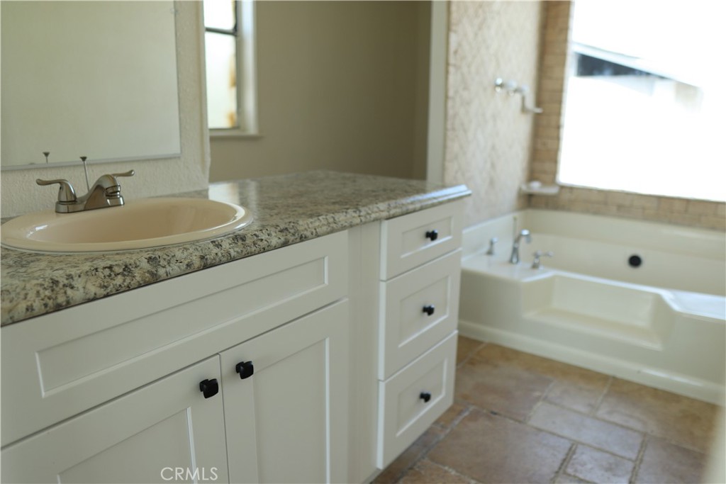 1855 East Riverside Drive, Unit 48 Ontario, CA 91761 - Photo 7 of 20 a bathroom with a granite countertop sink and a mirror a bathtub