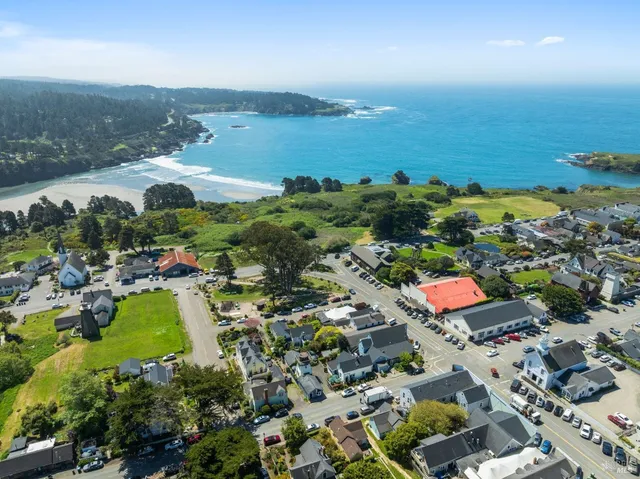 an aerial view of ocean and residential houses with outdoor space