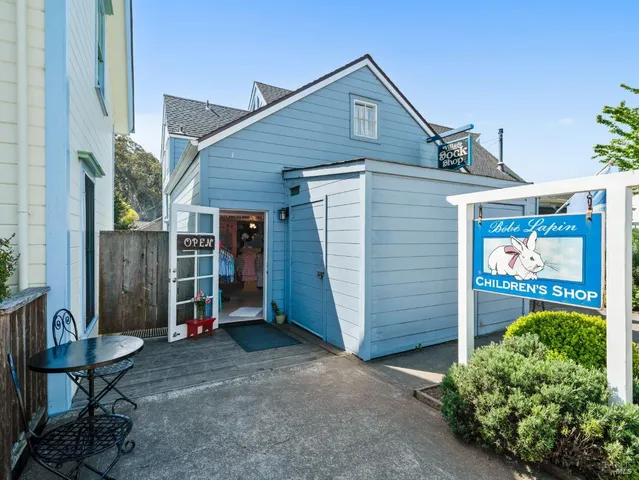 a view of a house with a barbeque and wooden bench