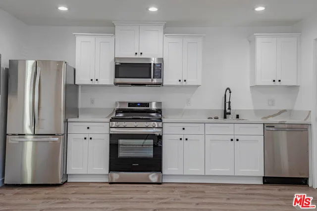 a kitchen with white cabinets stainless steel appliances and wooden floor
