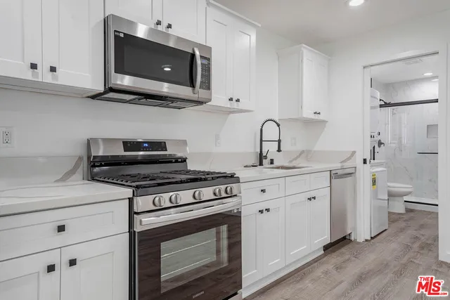 a kitchen with stainless steel appliances granite countertop a stove a microwave and a white cabinets