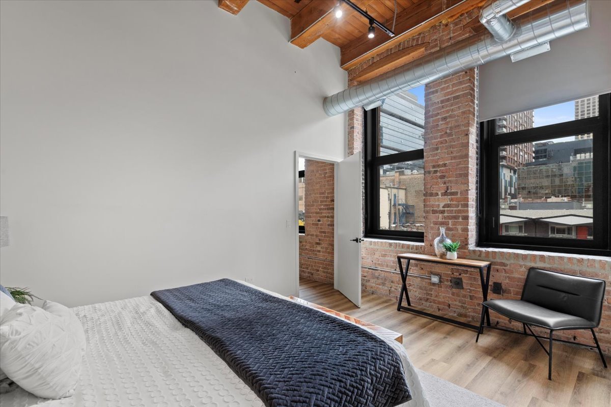 153 West Ohio Street, Unit 202 Chicago, IL 60654 - Photo 6 of 11 a bedroom with a bed and wooden floor