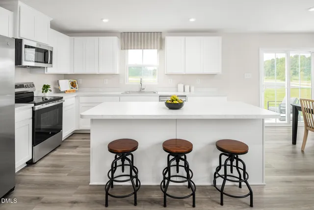 a kitchen with a refrigerator a stove a sink and white cabinets with wooden floor