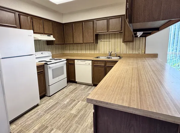 a kitchen with granite countertop a sink a stove and refrigerator