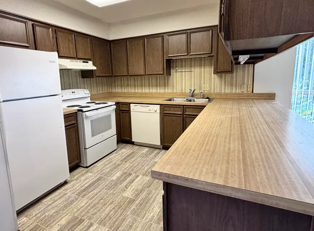 a kitchen with granite countertop a sink a stove and refrigerator