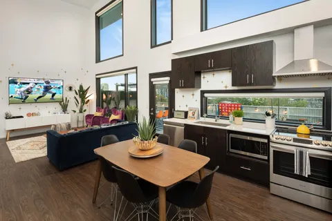 a kitchen with a stove a sink dishwasher a dining table and chairs with wooden floor