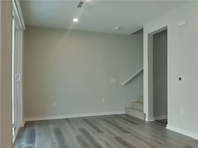 an empty room with wooden floor and entrance