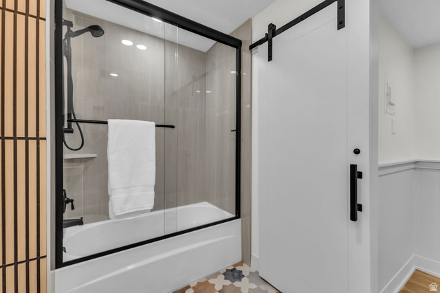 88 West 50 South, Unit C8 Centerville, UT 84014 - Photo 18 of 29 Bathroom featuring a white tub with a black-framed glass shower enclosure, matte black shower fixtures, and light-colored vertical tile work