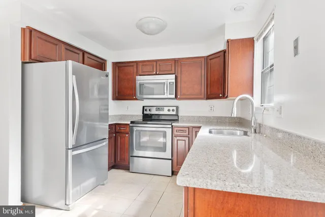 a kitchen with granite countertop a refrigerator stove and sink