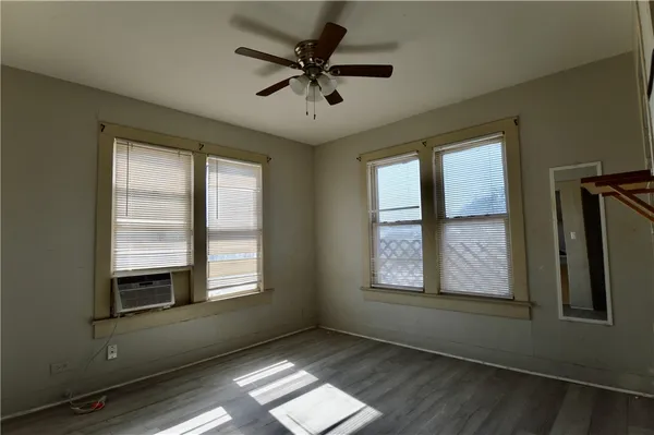 a view of an empty room with a window and wooden floor