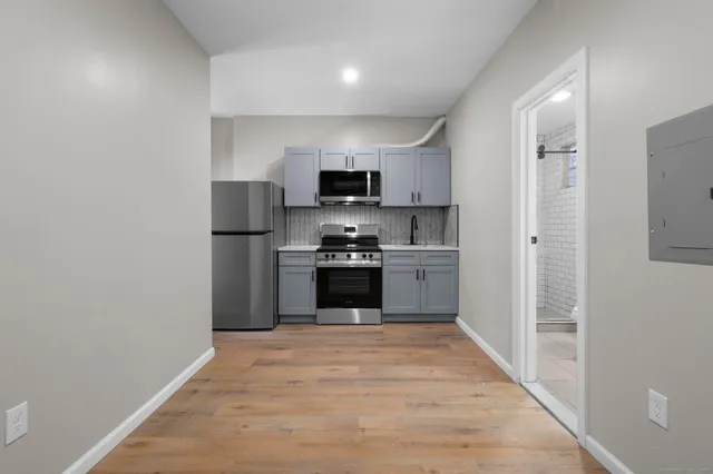 a kitchen with granite countertop a refrigerator and a stove top oven