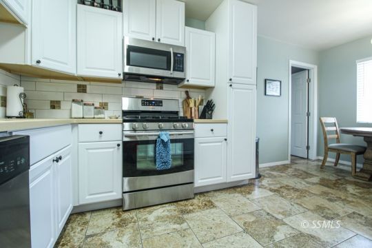 708 West Perdew Avenue Ridgecrest, CA 93555 - Photo 11 of 37 a kitchen with stainless steel appliances granite countertop a stove a sink and a microwave