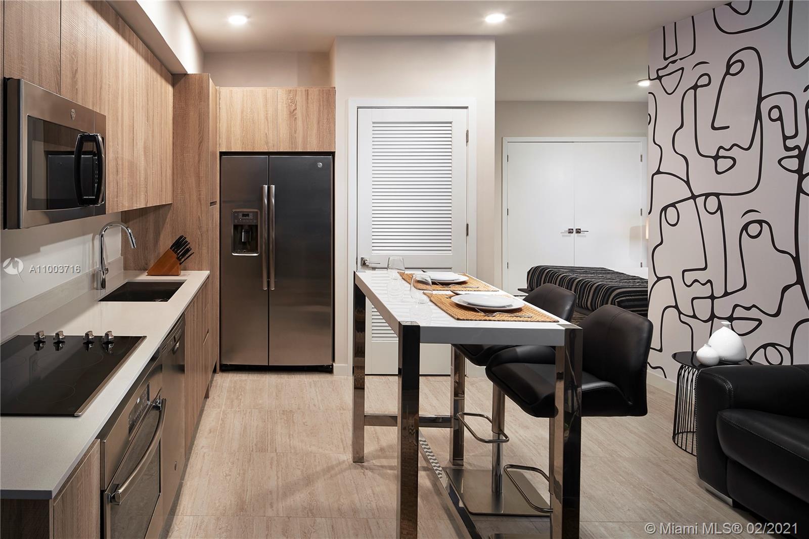 3900 Biscayne Boulevard, Unit N723 Miami, FL 33137 - Photo 10 of 15 a kitchen with stainless steel appliances kitchen island granite countertop a stove a sink dishwasher and a refrigerator with wooden floor