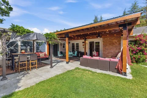 a view of a patio with table and chairs potted plants and large tree