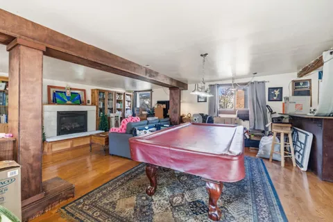 a living room with furniture a pool table and a fireplace