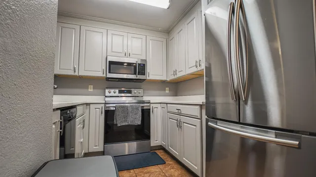 a kitchen with stainless steel appliances granite countertop a refrigerator a stove a sink and white cabinets with wooden floor