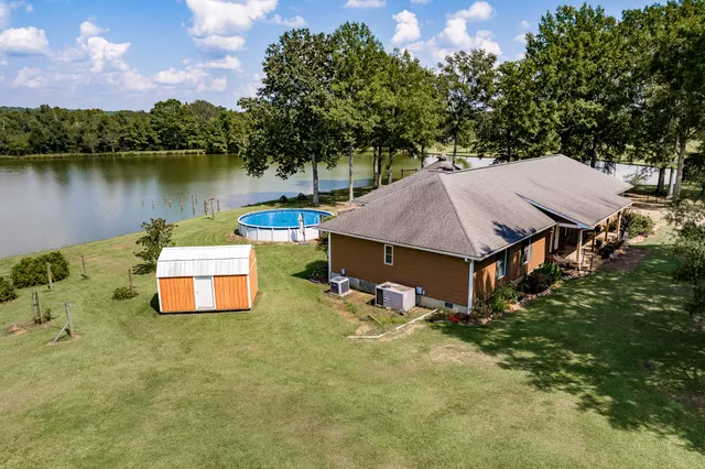 an aerial view of a house with swimming pool and lake view