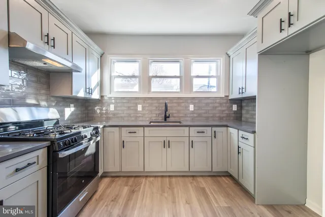 a kitchen with stainless steel appliances granite countertop a stove a sink and white cabinets