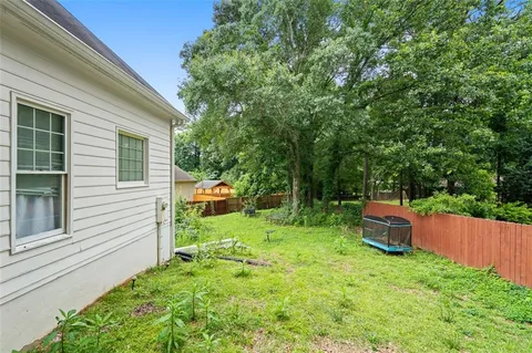 a view of a backyard with large trees and wooden fence