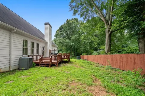a view of a backyard with table and chairs potted plants and large tree
