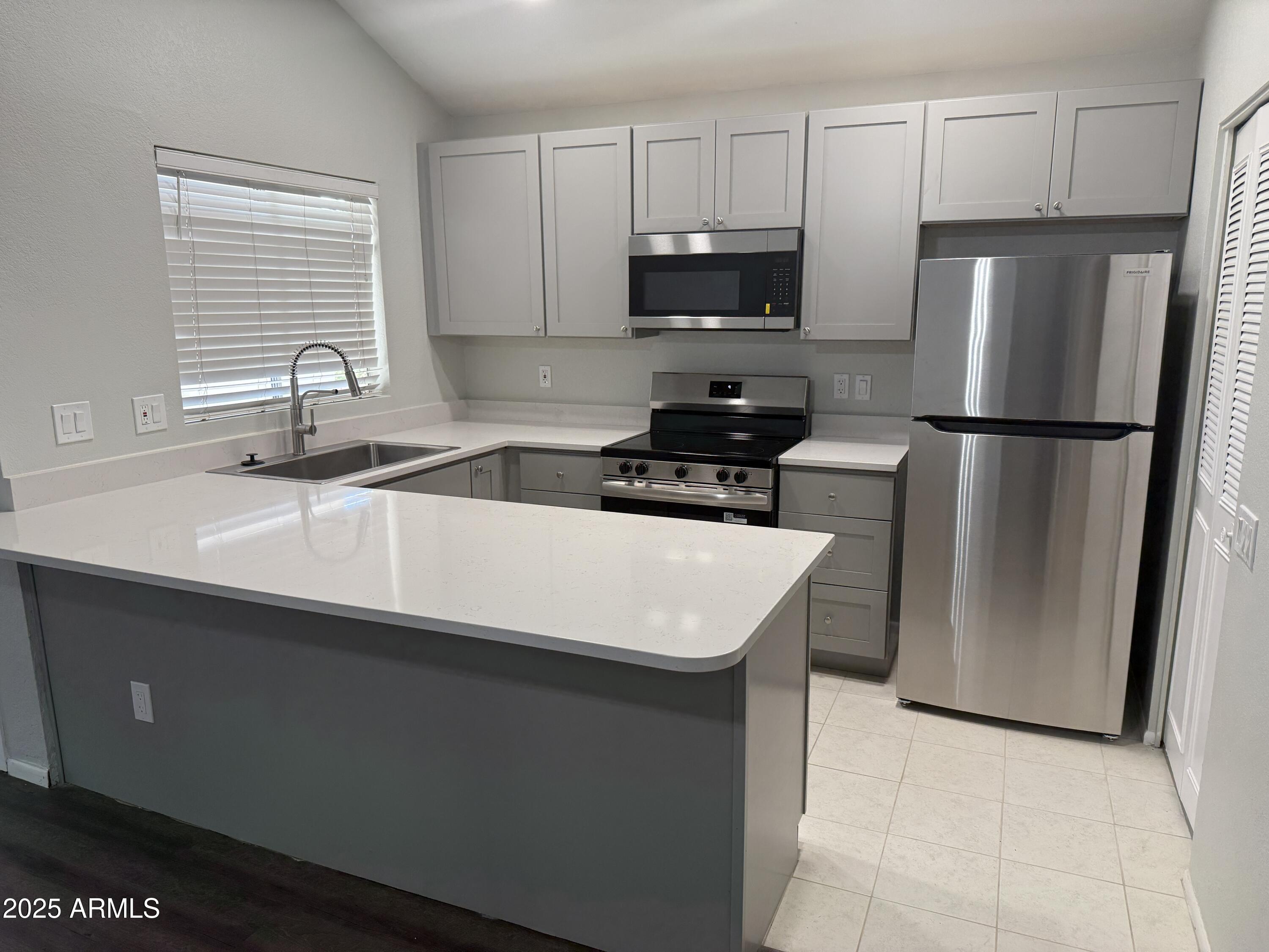 a kitchen with a sink a refrigerator a microwave and cabinets