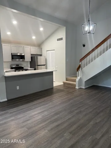 a view of kitchen with stainless steel appliances wooden floor and refrigerator