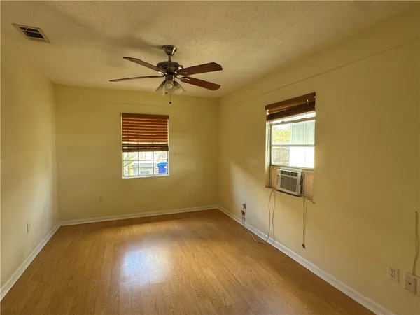 a view of empty room with wooden floor and fan