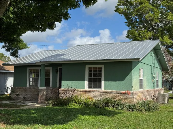a view of a white house with a yard and plants