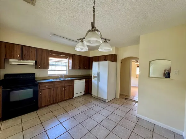 a kitchen with stainless steel appliances granite countertop a refrigerator a sink dishwasher a stove with wooden cabinets and floor