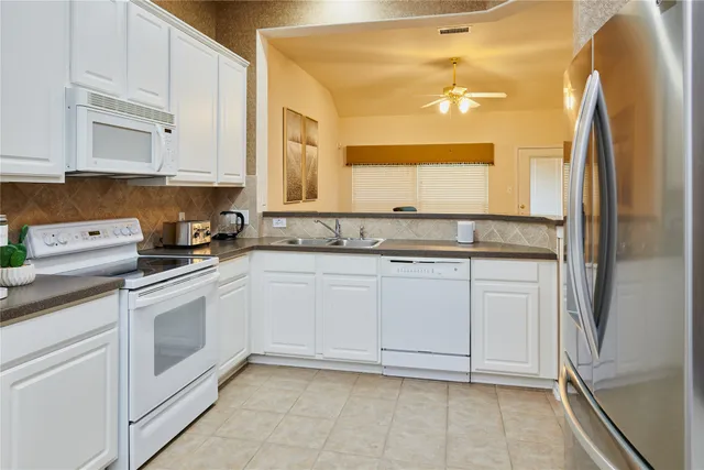 a kitchen with stainless steel appliances granite countertop white cabinets and refrigerator